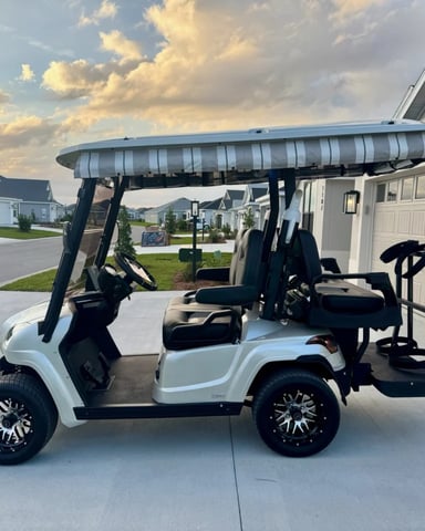 White golf cart with canopy and bike rack on driveway, suburban neighborhood in background