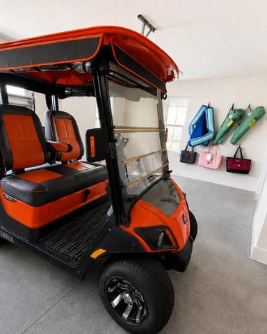 Red and black golf cart with canopy parked in garage with water sports equipment on wall